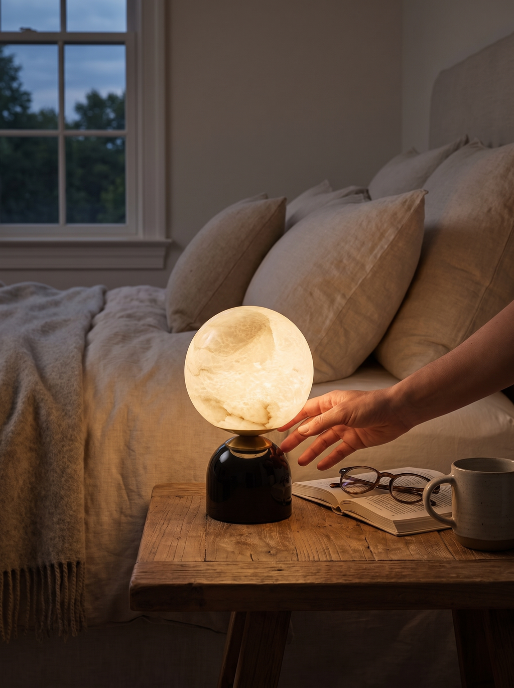 GOODNEST LUNA table lamp casting warm light beside a bed